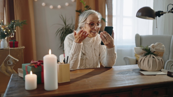 A happy senior woman making a video call with at Christmas time indoors at home.