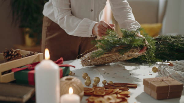 An unrecognizable senior woman making Christmas wreath from natural eco materials indoors at home