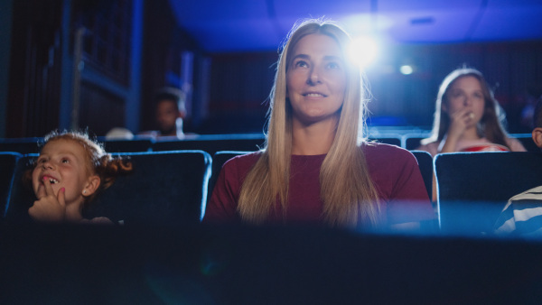 A front view of cheerful young woman in the cinema, watching film.