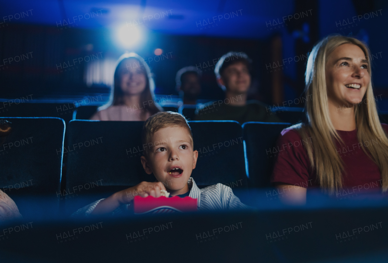 A mother with happy small children in the cinema, watching film.