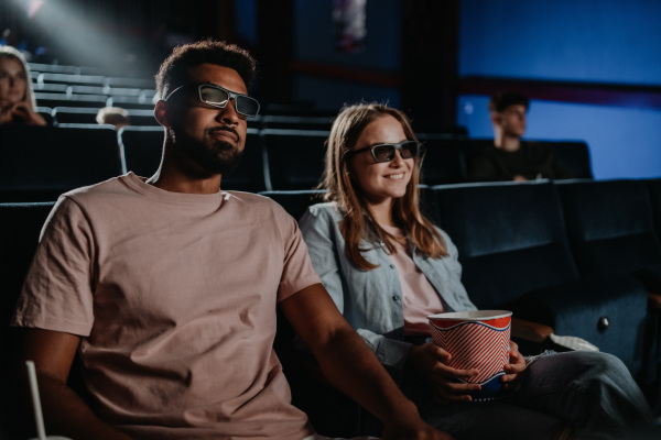 A cheerful young couple with 3d glasses in the cinema, watching film.