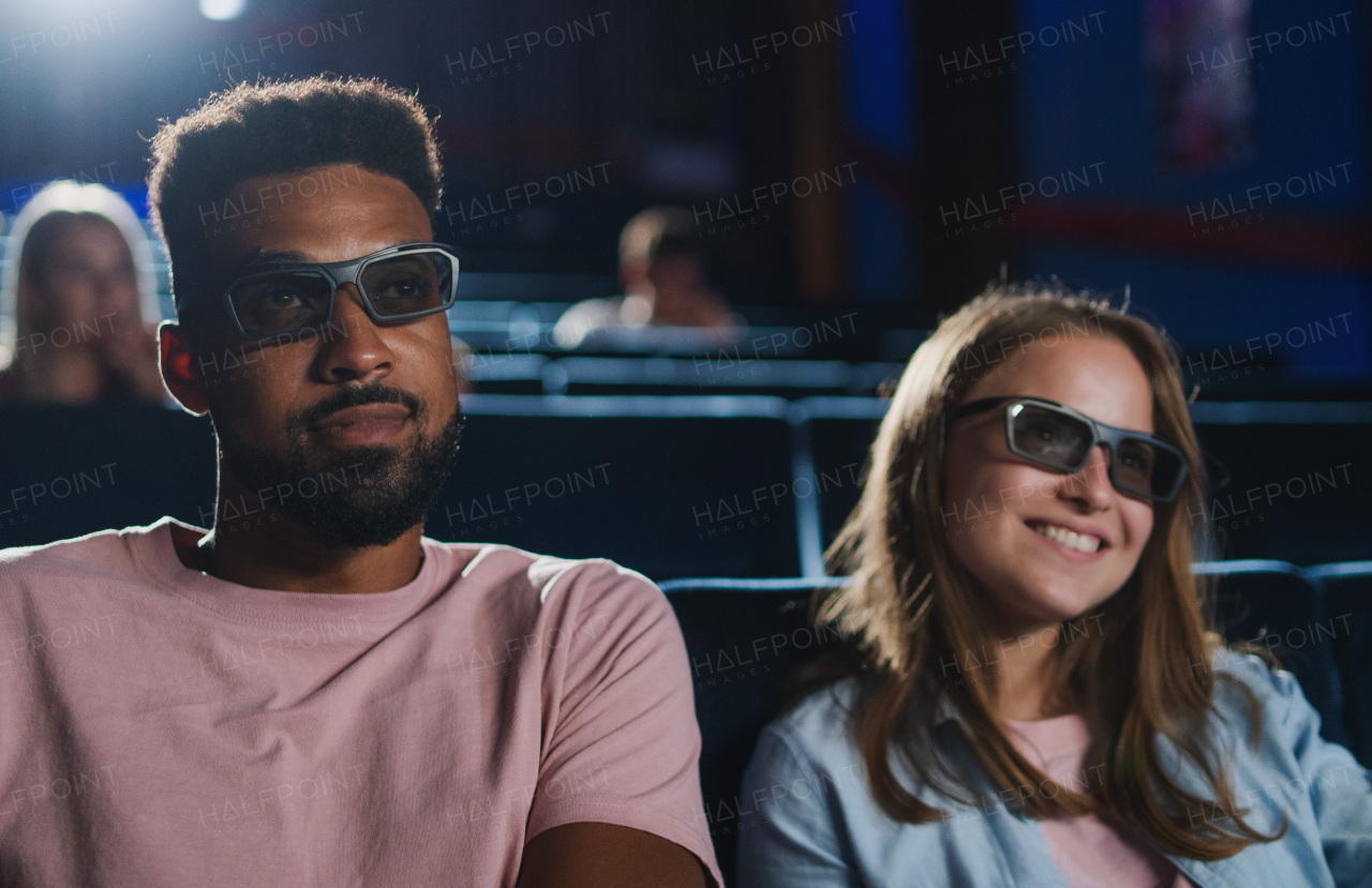 A cheerful young couple with 3d glasses in the cinema, watching film.