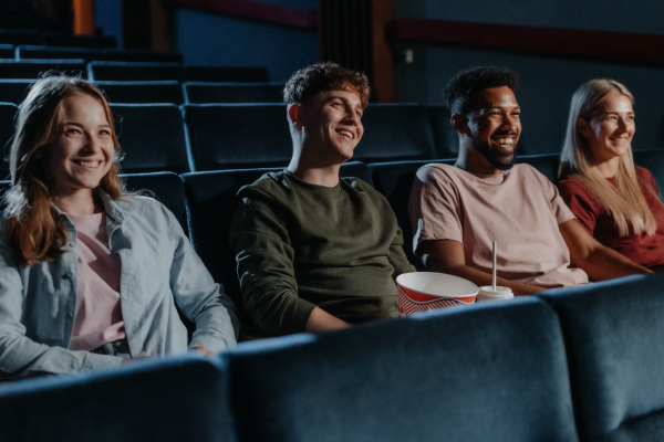 Young people with popcorn in the cinema, watching a thriller film.