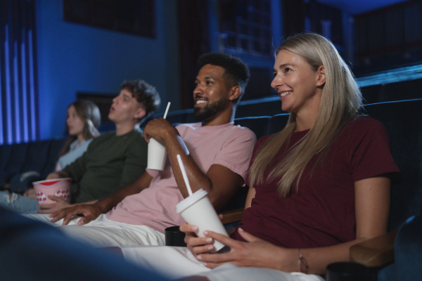 Cheerful young people sitting in the cinema, watching a film.