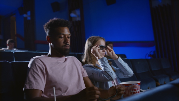 A cheerful young couple putting on 3d glasses in the cinema.