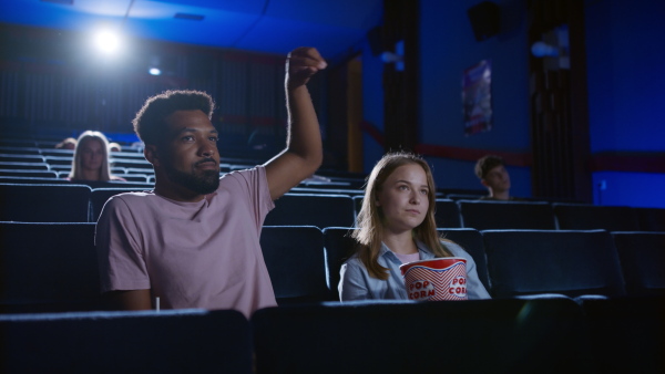 A cheerful young couple with popcorn in the cinema watching a movie.