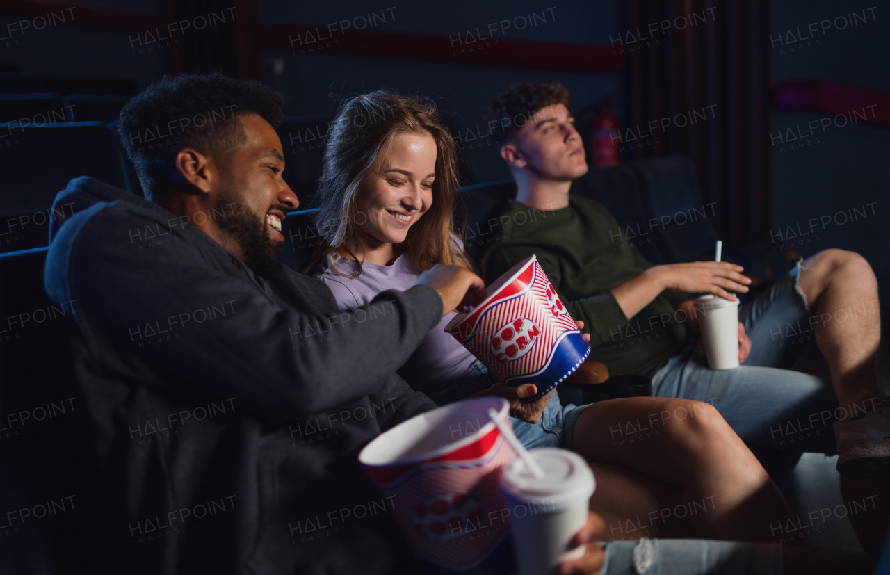 A cheerful young couple with popcorn in the cinema, talking.