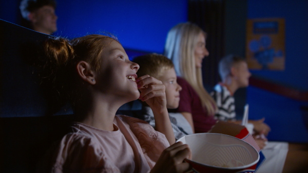 A mother with happy small children in the cinema, watching film.