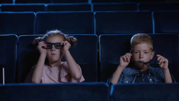 Happy small children putting on 3d glasses in the cinema, watching film.