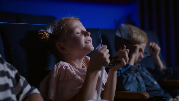 Happy small children putting on 3d glasses in the cinema, watching film.