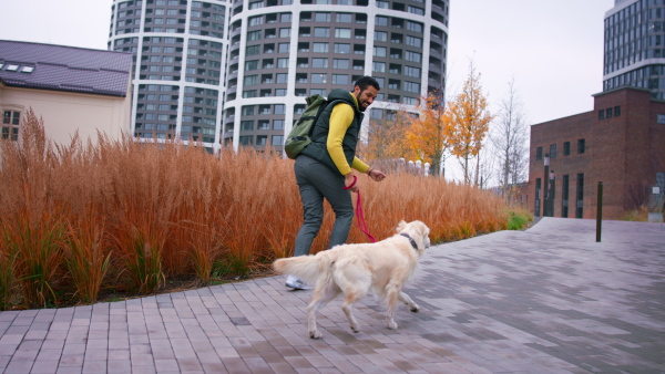 A high angle view of happy young man running upstairs with his dog outdoors in city.