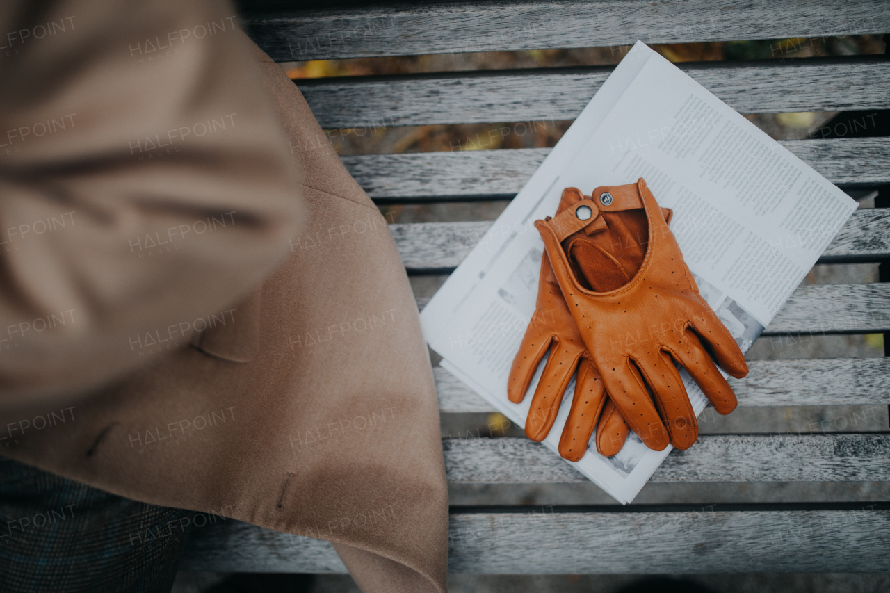 Top view of leather gloves and a newspaper on bench in park, autumn atmosphere.