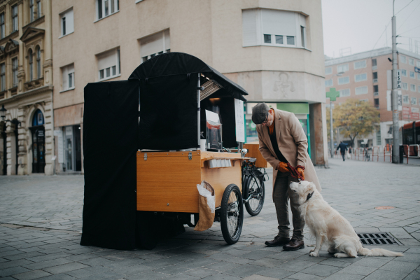 Elegant senior man walking his dog and buiyng street coffee outdoors in city.