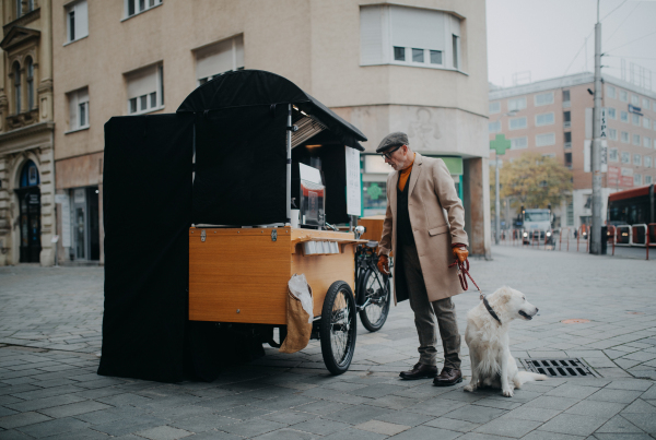 Elegant senior man walking his dog and buiyng street coffee outdoors in city.