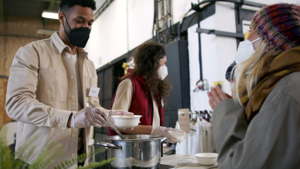 Volunteers serving hot soup for ill and homeless in community charity donation center, food bank and coronavirus concept.