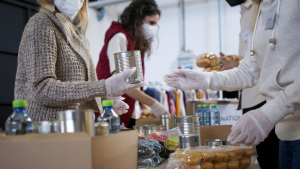 Group of volunteers in community donation center, food bank and coronavirus concept.