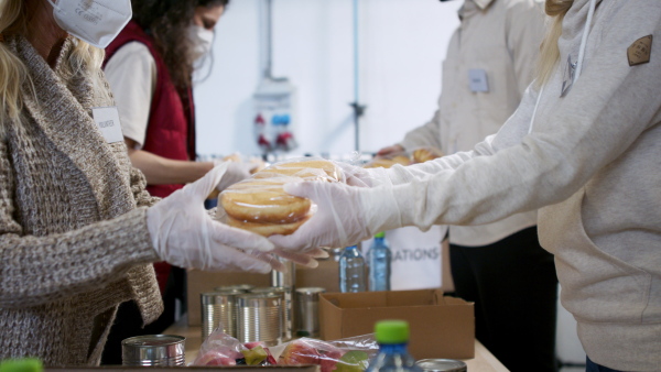 Group of volunteers in community donation center, food bank and coronavirus concept.