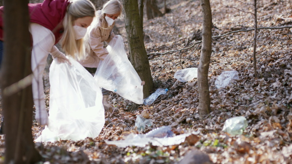 A group of volunteers picking up plastic waste from nature, looking at camera. Coronavirus concept.