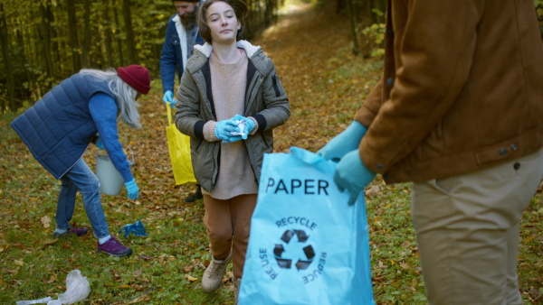 A diverse group of volunteers cleaning up forest from waste, community service concept