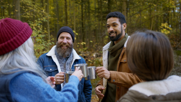 A diverse group of happy volunteers cleaning up forest, having break, drinking tea and talking together.