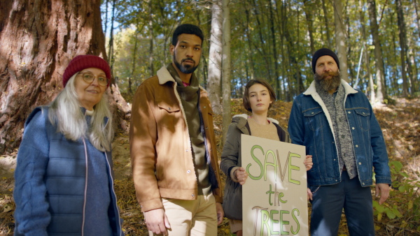 A diverse group of environmental activists with banner protestig against illegal construcion in forest