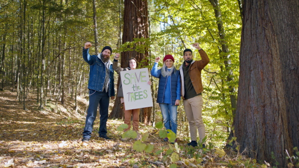 A diverse group of environmental activists with banner protestig against illegal construcion in forest