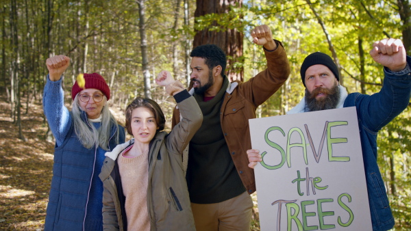 A diverse group of environmental activists with banner protestig against illegal construcion in forest