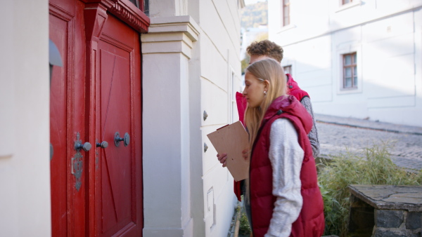 Young door to door volunteers talking to senior woman and taking a survey at her front door.