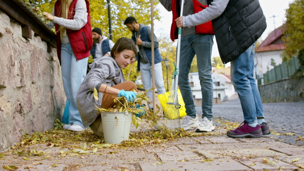 A diverse group of happy volunteers cleaning up street, community service concept