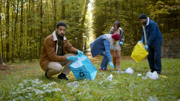 A diverse group of volunteers cleaning up forest from waste, community service concept