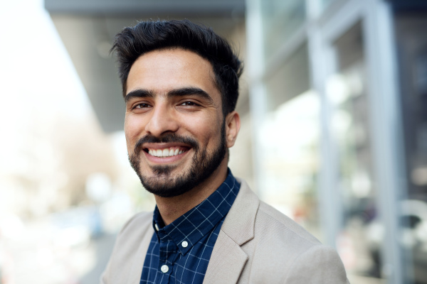 Front view portrait of young businessman commuter outdoors in city, looking at camera