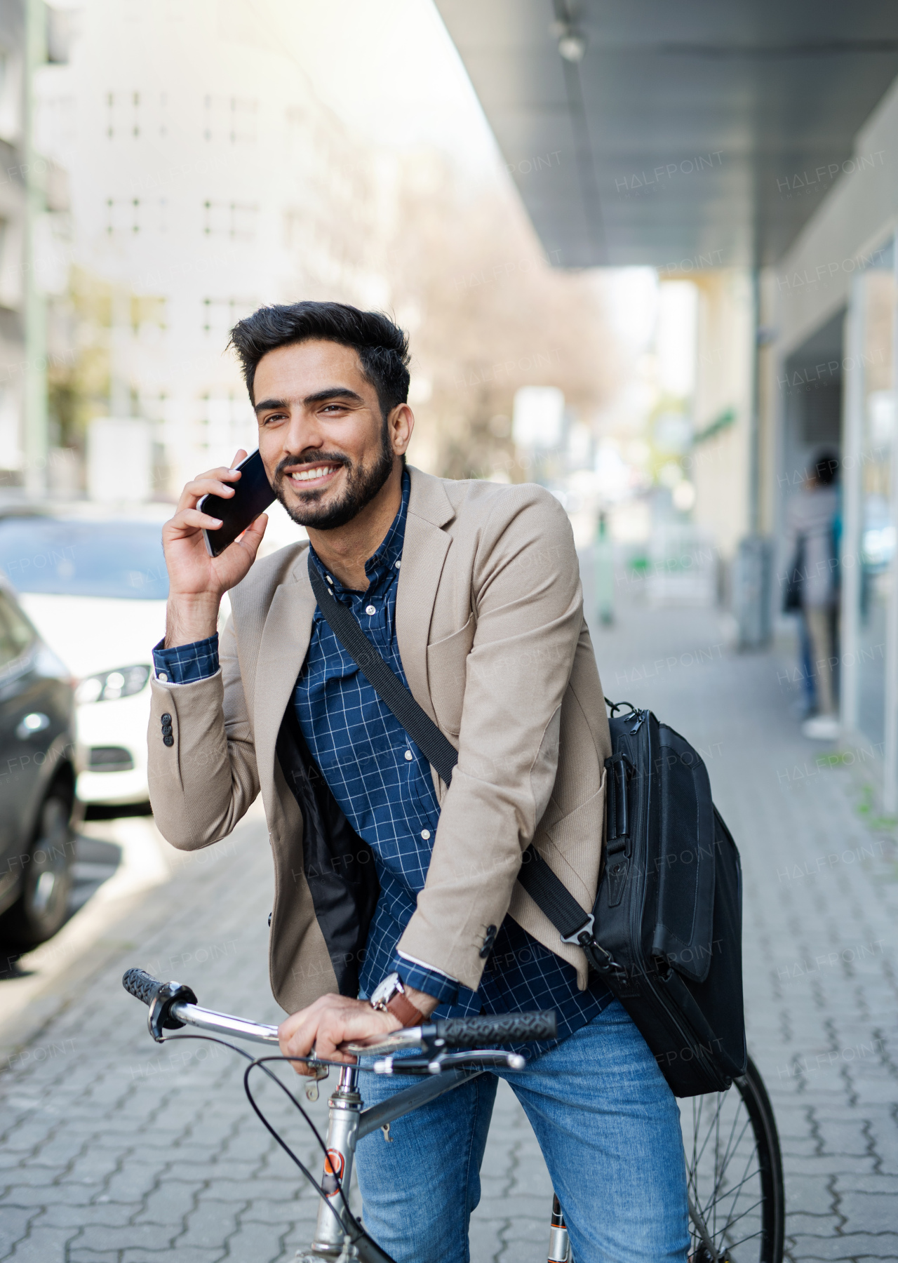 Portrait of young business man commuter with bicycle with smartphonegoing to work outdoors in city.