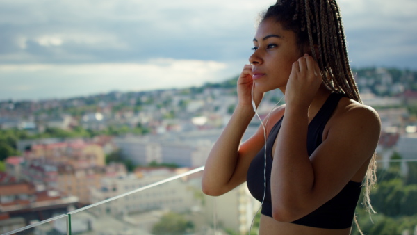 A young sport woman preparing for doing exercise on balcony outdoors in city in the morning.