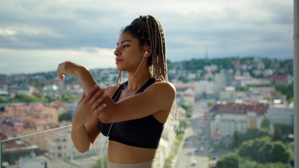 A young sport woman doing exercise on balcony outdoors in city in the morning.