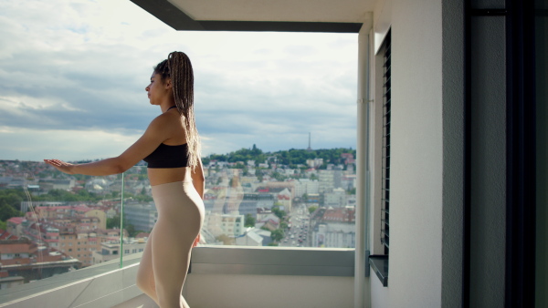 A young sport woman doing exercise on balcony outdoors in city in the morning.