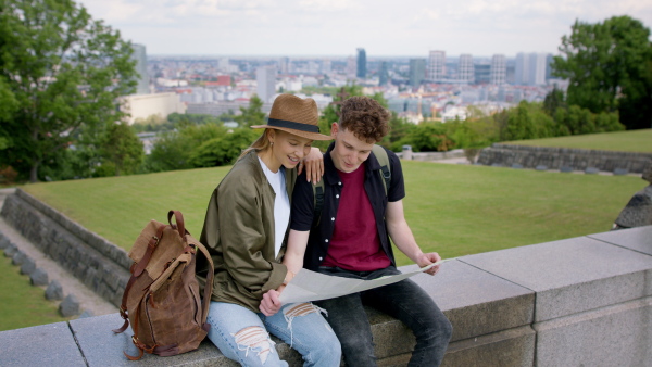 Young couple travelers walking with map in city on holiday, sightseeing.