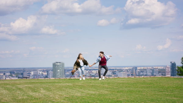 A cheerful young couple travelers in city on holiday, jumping. Cityscape in the background.