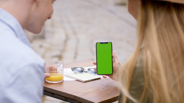 An unrecognizable couple travelers with smartphone in city on holiday. Chroma key concept.