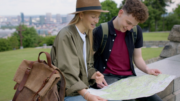 Young couple travelers walking with map in city on holiday, sightseeing.