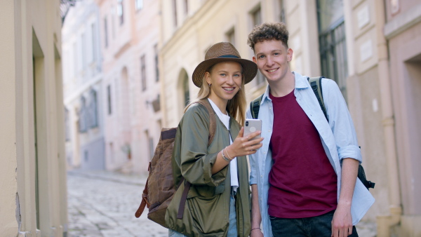 Young couple travelers walking with smarthone in city on holiday, sightseeing and looking at camera.