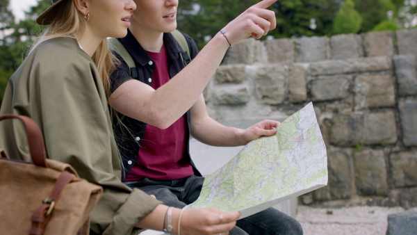 Young couple travelers walking with map in city on holiday, sightseeing.