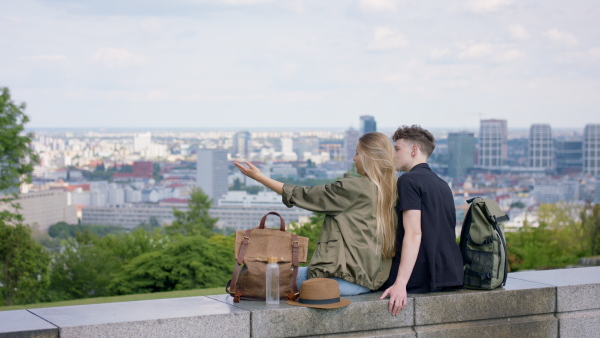 A rear view of young couple travelers in city looking at view, coronavirus concept.