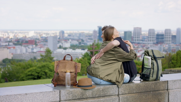 Happy young couple travelers in city on holiday, hugging. Cityscape in the background.