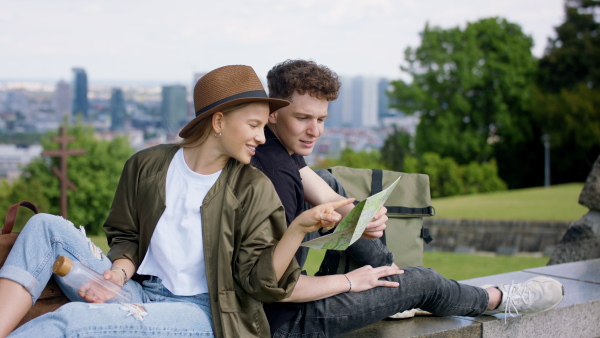 Young couple travelers walking with map in city on holiday, sightseeing.