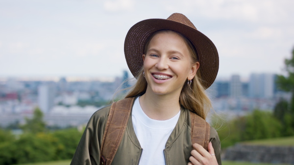 A teenage girl in city on holiday, looking at camera. Cityscape in the background.