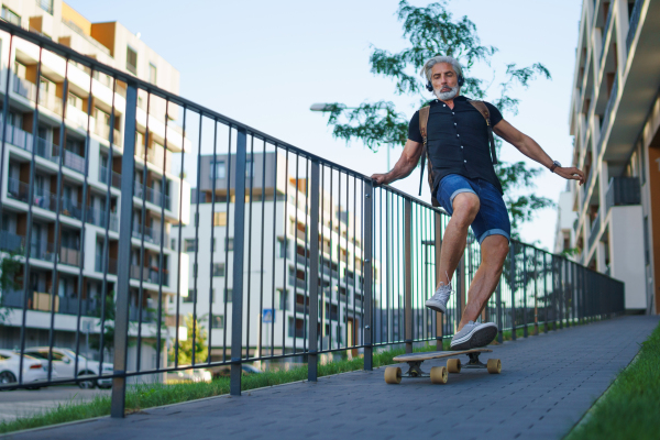 Front view portrait of mature man riding skateboard outdoors in city, going back to work.