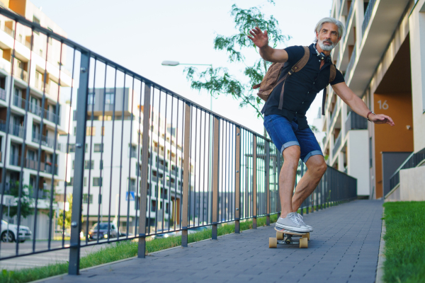 Front view portrait of mature man riding skateboard outdoors in city, going back to work.