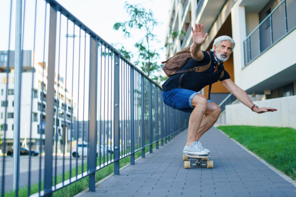 Front view portrait of mature man riding skateboard outdoors in city, going back to work.