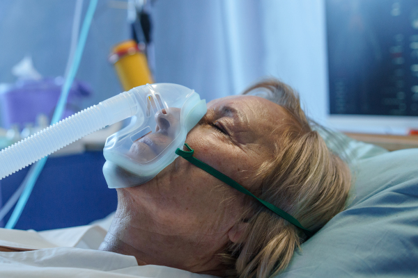 Close-up of covid-19 infected patient in bed in hospital, coronavirus and ventilation concept.