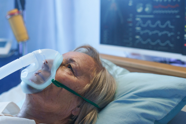 A close-up of covid-19 patient with oxygen mask in bed in hospital, coronavirus concept.